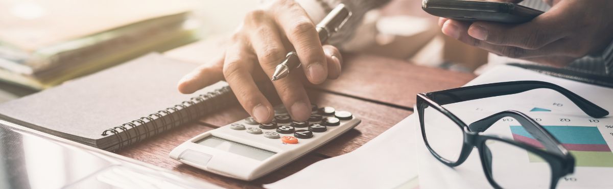 Image of desk with calculator glasses & note pad